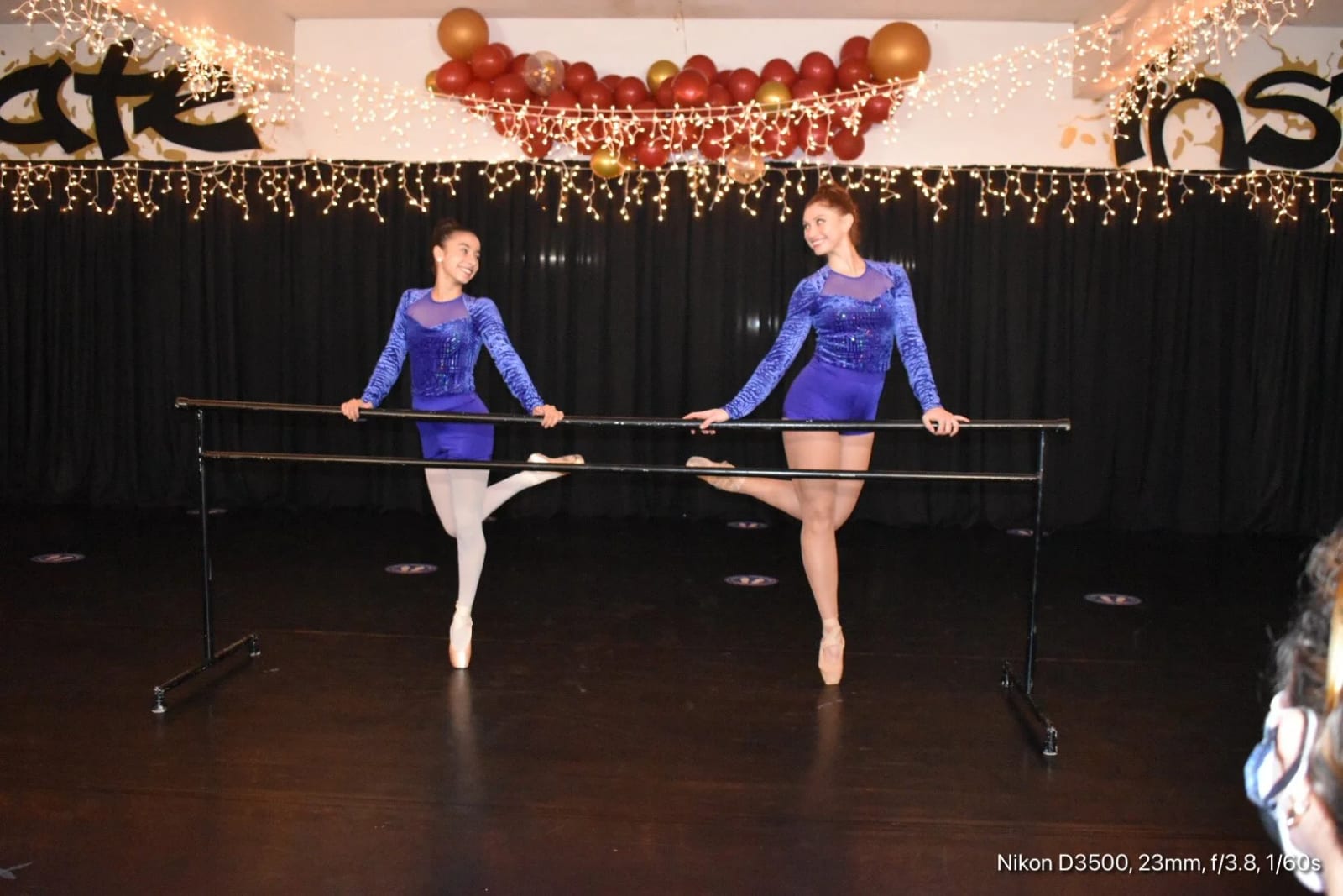 Two dancers in blue sequin costumes at a portable barre on our showcase stage.
