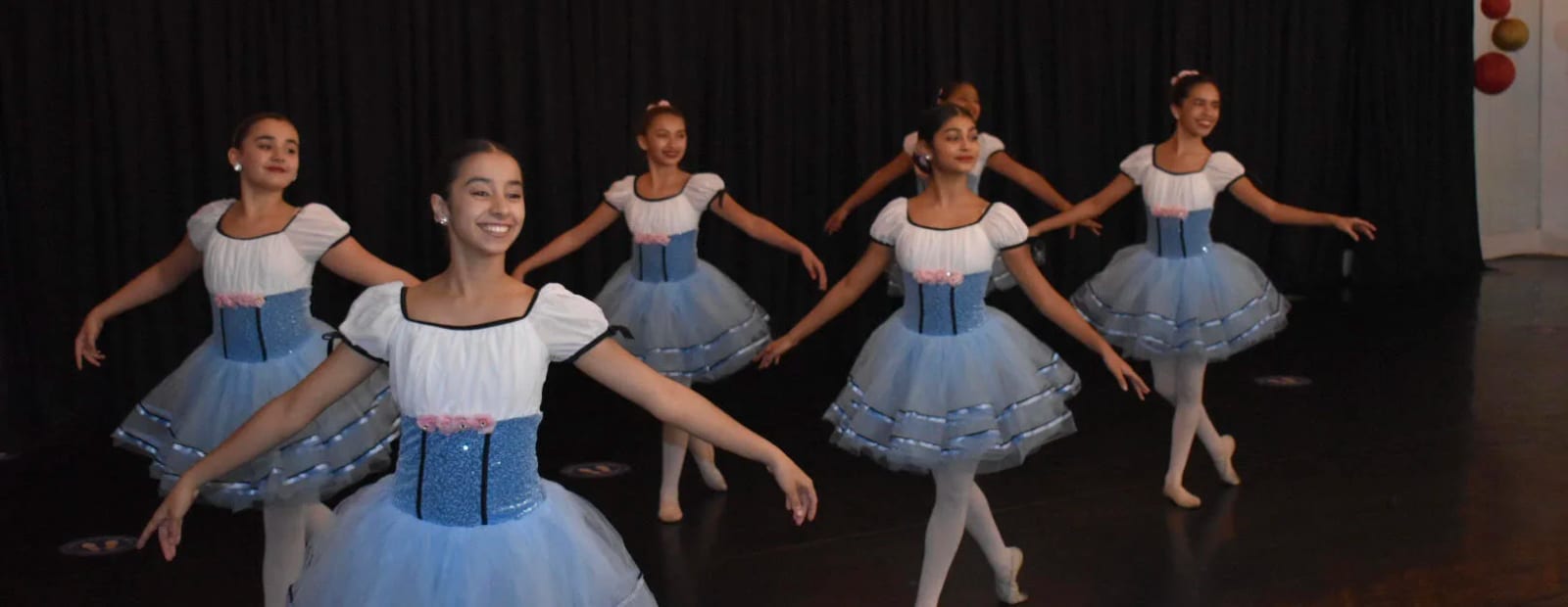 A ballet group in blue and white romantic tutus spread across the stage.