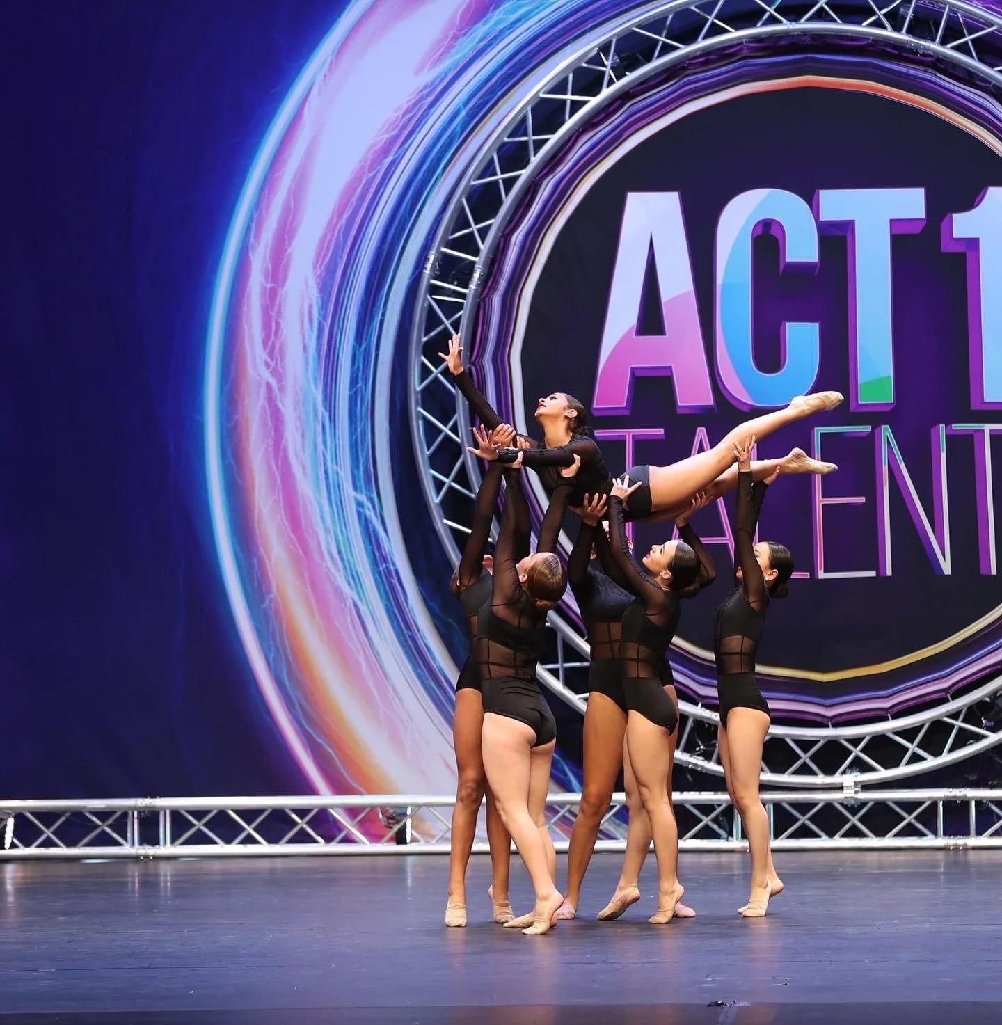 Four of our dancers in a group pose on a competition stage.