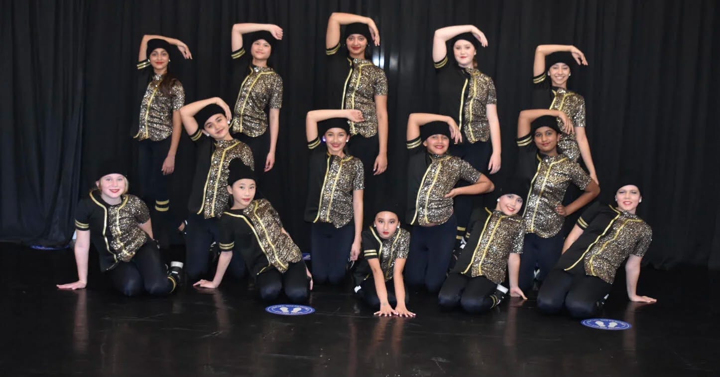 Our hip-hop dancers in camo shirts posed in rows on a dark stage.