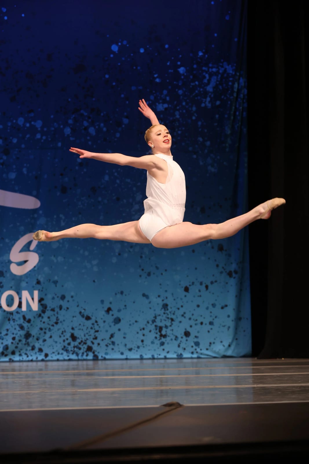 One of our dancers mid-leap in front of a blue sequin backdrop.